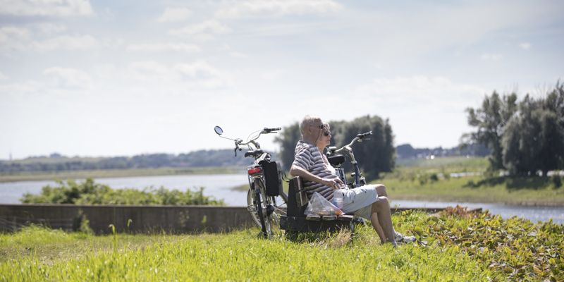 Koppel rustend op een houten bank met uitzicht op de Maas