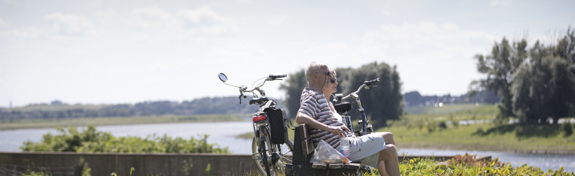 Koppel rustend op een houten bank met uitzicht op de Maas